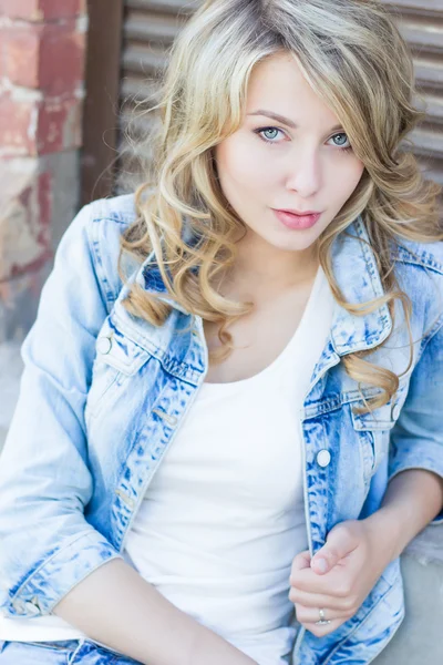 Beautiful funny blonde girl with big lips with a charming smile, wearing jeans and a white shirt walking in the city solnetsnym summer day — Stock Photo, Image