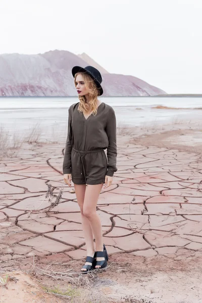 Fashion shot of a beautiful sexy girl in a black hat is removed in the desert for the magazine — Stock Photo, Image