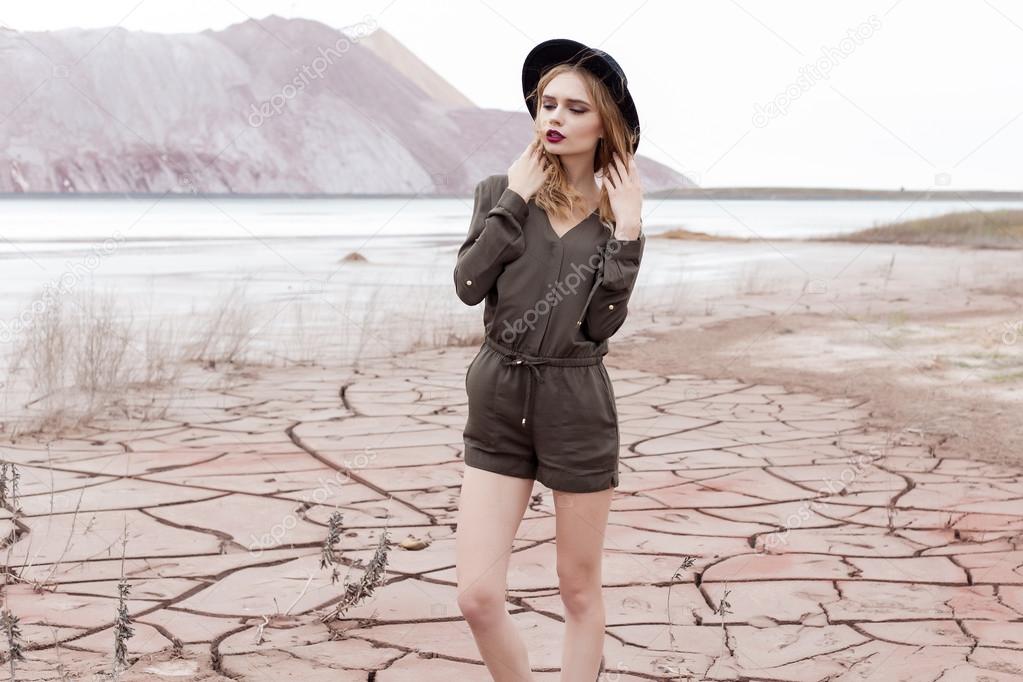 fashion shot of a beautiful sexy girl in a black hat is removed in the desert for the magazine