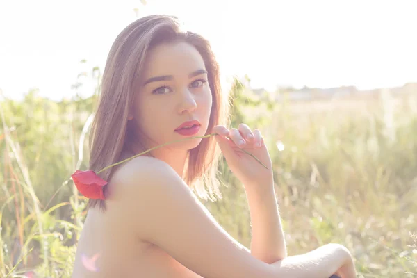 Mooie lieve meid met grote lippen mollige met papaver in de hand lopen in een veld op een zonnige dag bij zonsondergang met bared schouders — Stockfoto