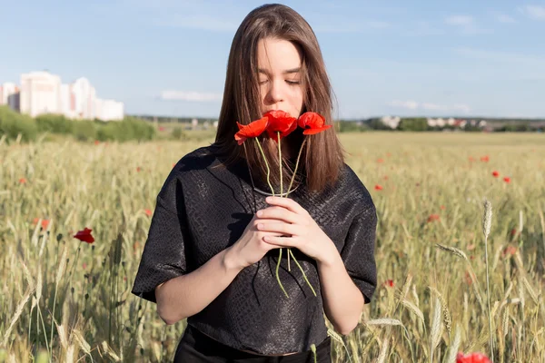 Hermosa linda mujer joven sexy con los labios llenos de pelo corto en un campo con flores de amapola en sus manos —  Fotos de Stock