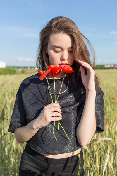 Belle jeune femme sexy mignonne avec les lèvres pleines avec les cheveux courts dans un champ avec des fleurs de pavot dans leurs mains — Photo