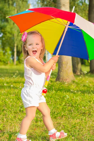 Little fun beautiful girl walks in the Park with colorful umbrella — Stock Photo, Image