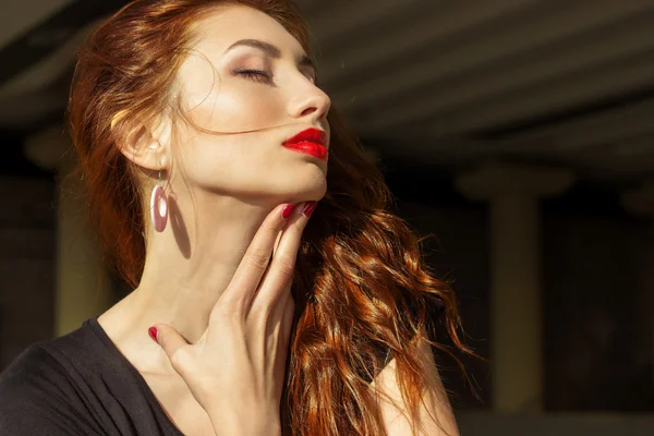 Beautiful sexy girl with red hair with big red lips with makeup in the city on a Sunny summer day — Stock Photo, Image