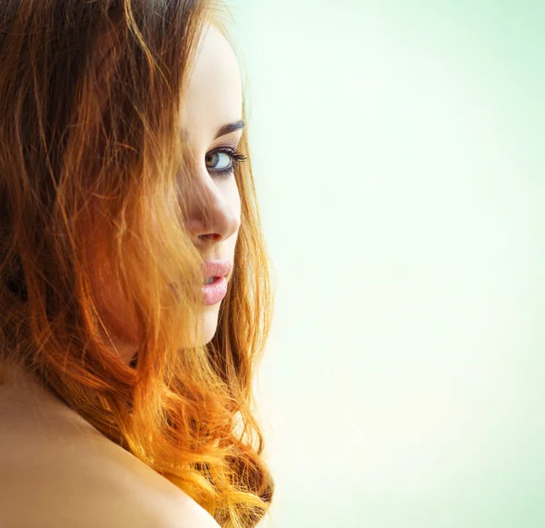 Красива сексуальна дівчина з довгим рудим волоссям з зеленими очима, що дивиться на плече на білому тлі — стокове фото