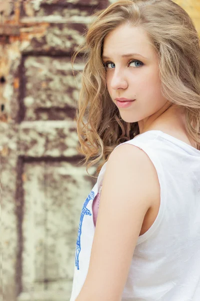 Portrait of beautiful girl with full lips in a white t-shirt standing on the street near the old building — Stock Photo, Image