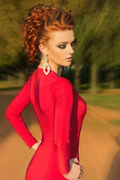 Bella ragazza elegante con bel trucco e capelli in un abito da sera rosso nel parco — Foto Stock