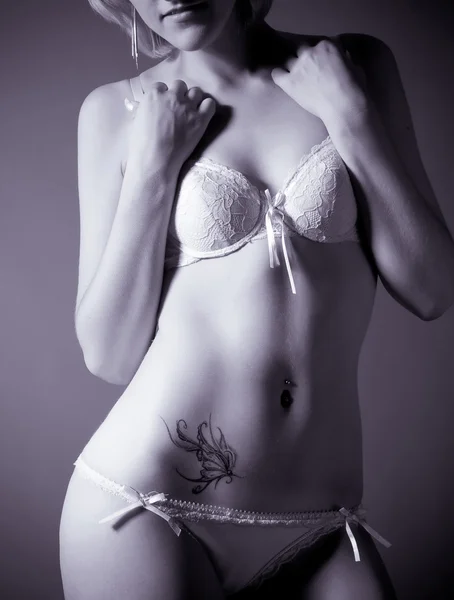 Mooie sexy slim meisje met een vlinder tatoeage op zijn buik — Stockfoto