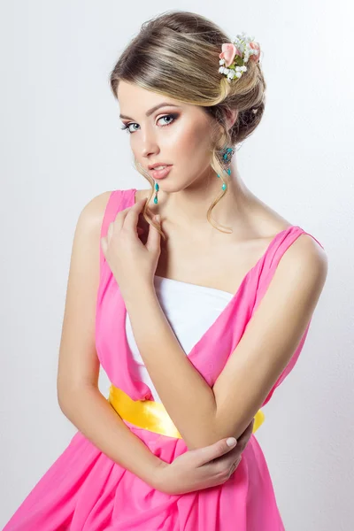 Ніжний образ красивої дівчини як нареченої з яскравою зачіскою для макіяжу з квітами трояндами в голові в довгій рожевій сукні — стокове фото