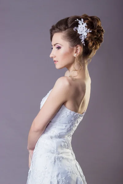 Ritratto di una bella sposa donna gentile ed elegante in un vestito bianco con una bella acconciatura e trucco — Foto Stock