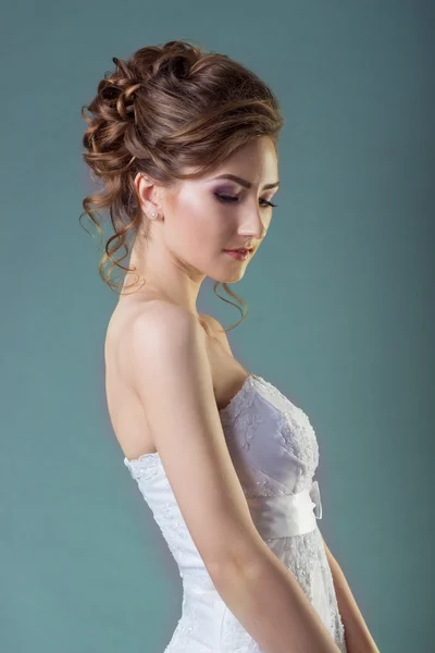 Retrato de una hermosa novia de mujer suave y elegante en un vestido blanco con un hermoso peinado y maquillaje — Foto de Stock