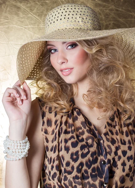 Hermosa mujer joven sexy en el vestido de leopardo maquillaje brillante en el estudio sobre un fondo de oro en el sombrero —  Fotos de Stock