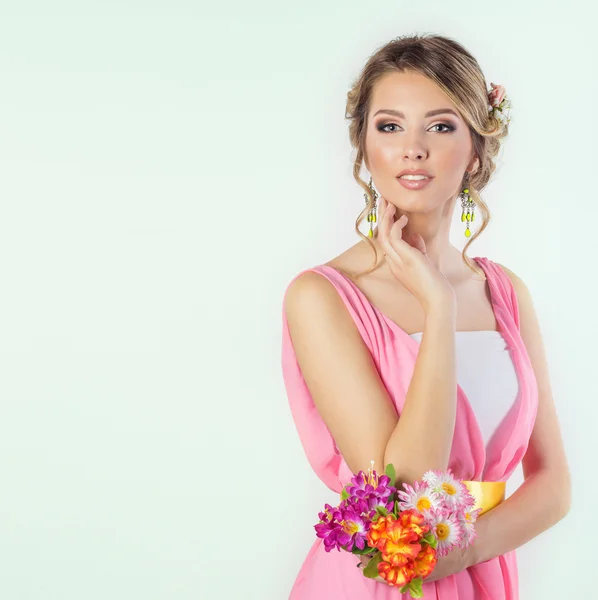 Imagem delicada de uma bela mulher menina como uma noiva com penteado de maquiagem brilhante com flores rosas na cabeça em um vestido rosa longo com flores na mão Imagem De Stock