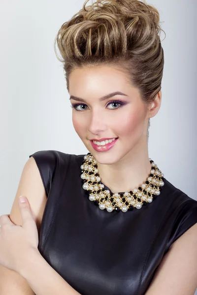 Porträt einer schönen glücklichen sexy jungen Frau, die in einem schwarzen Abendkleid mit Haaren und Make-up mit teurem Schmuck im Studio auf weißem Hintergrund lächelt — Stockfoto