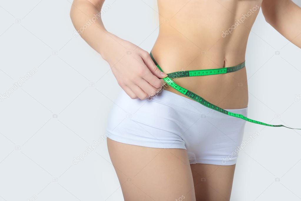 Young sports a beautiful slim woman measuring perfect shape nice hips, the concept of a healthy lifestyle on a white background
