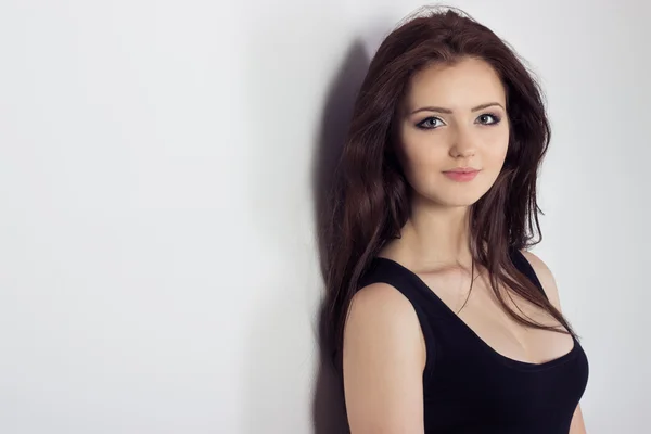 Porträtt av en vacker söt ung tjej med långt hår i studion på en vit bakgrund mot väggen — Stockfoto