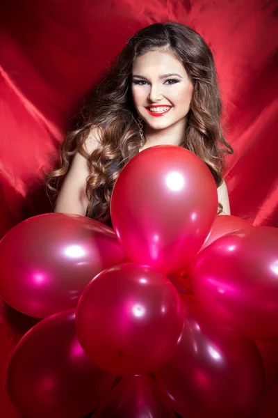 Schöne elegante, glückliche junge Frau mit roten Kugeln in den Händen mit rotem Lippenstift — Stockfoto