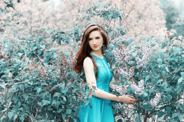 Jovem menina bonita em um dia de verão andando entre as flores de lilás no Parque — Fotografia de Stock