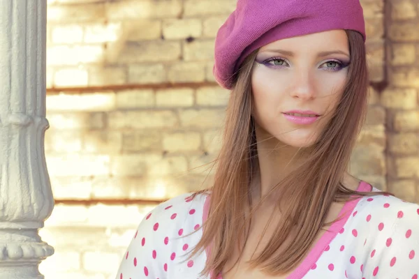 Hermosa chica sexy en un sombrero rosa con hermoso maquillaje en la chaqueta blanca en lunares rosados se encuentra en un día soleado de otoño en el Parque cerca de las hojas rojas —  Fotos de Stock