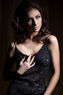 Hafif makyaj ve güzel saçlı karanlık aydınlatma stüdyoda siyah dantel elbise genç güzel seksi kız