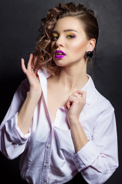 Giovane bella ragazza sexy con trucco luminoso e bei capelli in camicia bianca in Studio su uno sfondo nero con labbra paffute viola — Foto Stock