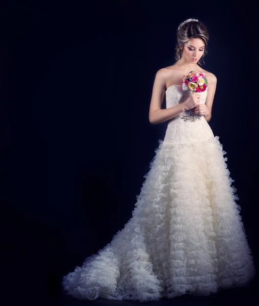 Schöne sanfte Frau glückliche Braut in einem weißen Hochzeitskleid mit einer Zugkabine mit einer schönen Hochzeitsfrisur mit weißen Blumen im Haar und einem kleinen Strauß in ihren Händen — Stockfoto