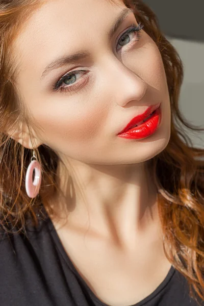 Beautiful sexy girl with red hair with red lipstick and beautiful makeup in a black t-shirt on a bright Sunny summer day Royalty Free Stock Photos