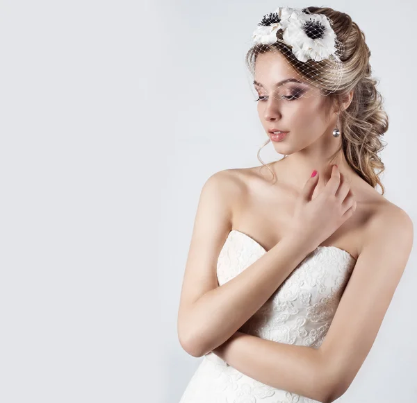 Glücklich schöne Braut Frau blonde Mädchen in einem weißen Hochzeitskleid, mit Haaren und hellem Make-up mit Schleier in den Augen und Blumen in den Haaren im Studio — Stockfoto