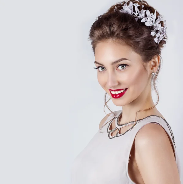 Linda jovem sexy elegante mulher sorridente feliz com lábios vermelhos, belo penteado elegante com flores brancas em seu cabelo, o caminho para a noiva em um casamento — Fotografia de Stock