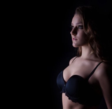 Güzel seksi kız ile bukleler siyah iç çamaşırı ve Studio siyah bir arka plan, yüzünde bir gülümseme ile parlak makyaj silüeti