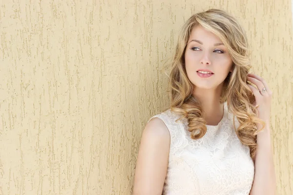 Portrait of a beautiful sexy smiling happy girl with big full lips with blond hair in a white dress on a sunny bright day — Stock Photo, Image