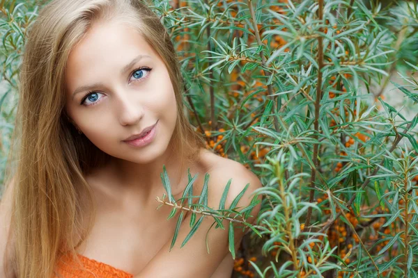 Beautiful sexy girl with big lips long hair with dark skin sits near sea buckthorn summer on a warm Sunny day — Stock Photo, Image