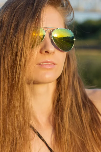 Сексуальная девушка с длинными волосами и кожей с загаром в солнцезащитных очках на пляже Солнечного теплого дня — стоковое фото