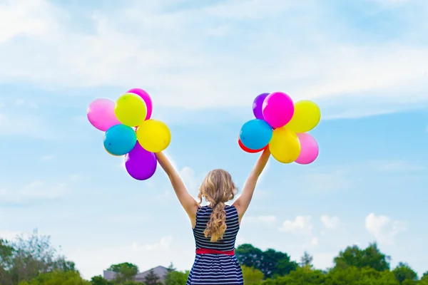 Vacker flicka spelar med färgglada ballonger i sommardag mot den blå himlen — Stockfoto