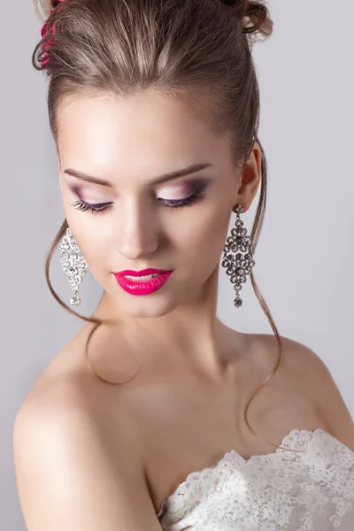 Retrato de moda de una hermosa chica atractiva con un suave y elegante peinado de boda por la noche maquillaje alto y brillante, con flores en el pelo y pendientes grandes —  Fotos de Stock