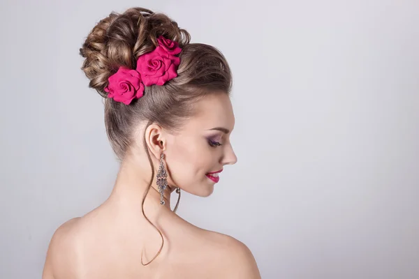 Modeporträt einer schönen attraktiven Mädchen mit einem sanften eleganten Abend Hochzeitsfrisuren hoch und hell Make-up, mit Blumen im Haar und große Ohrringe — Stockfoto