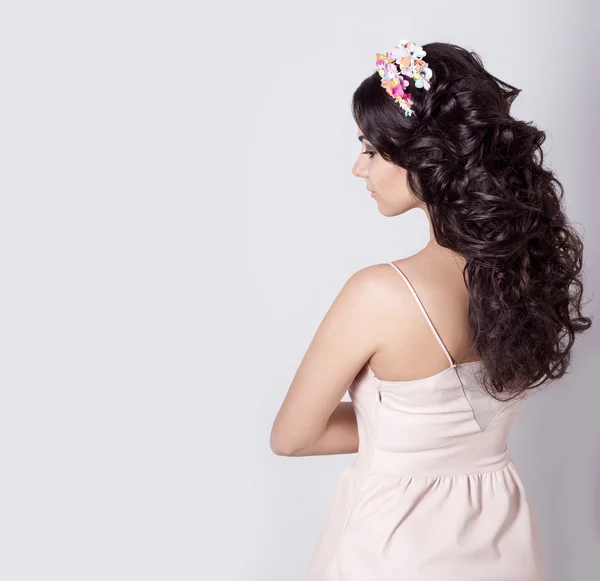 Menina bonita fazer seus cachos de cabelo no cabelo preto longo decorado com uma coroa de flores — Fotografia de Stock