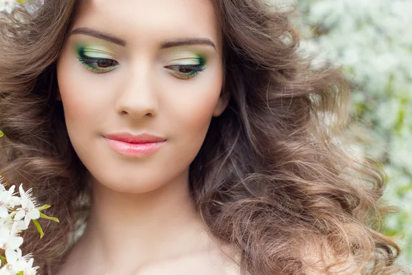 Beautiful sexy young tender sweet smiling girl in a flowered garden with beautiful makeup — Stock Photo, Image