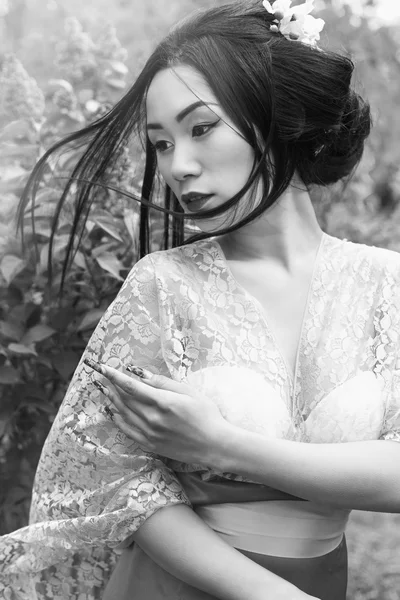 Chinês bela menina sexy em um quimono com uma bela maquiagem com cabelo andando em um jardim perto de arbustos floridos lilás — Fotografia de Stock