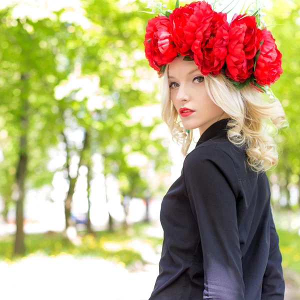 Retrato de una hermosa chica rubia sexy con una corona de peonía pasea por el jardín en un día soleado — Foto de Stock