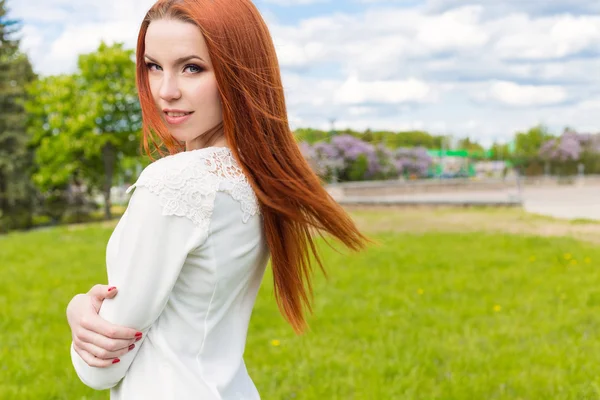Happy beautiful sexy red-haired girl in a white dress walks in the park — Stock Photo, Image
