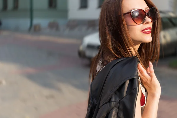 Beautiful cute sexy happy smiling brunette girl in the big sunglasses walking around the city at sunset — Stock Photo, Image