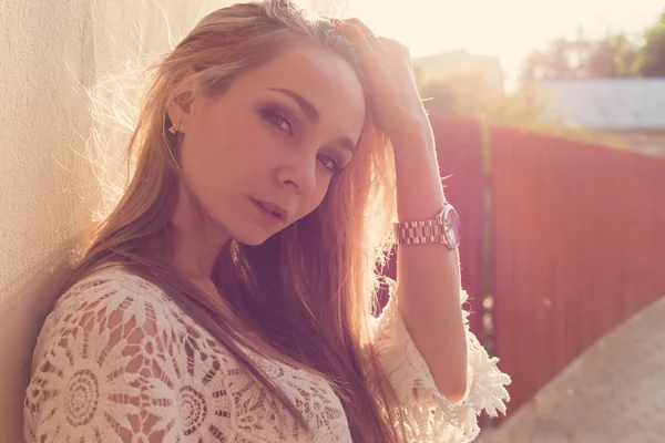 Beautiful sexy tender girl near the wall , next to a wooden fence at sunset in the city, volntse hair — Stock Photo, Image