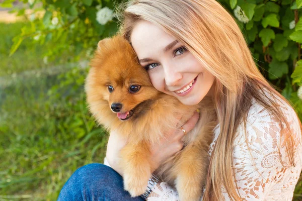 Happy beautiful gentle girl hugging her pet dog red Spitz