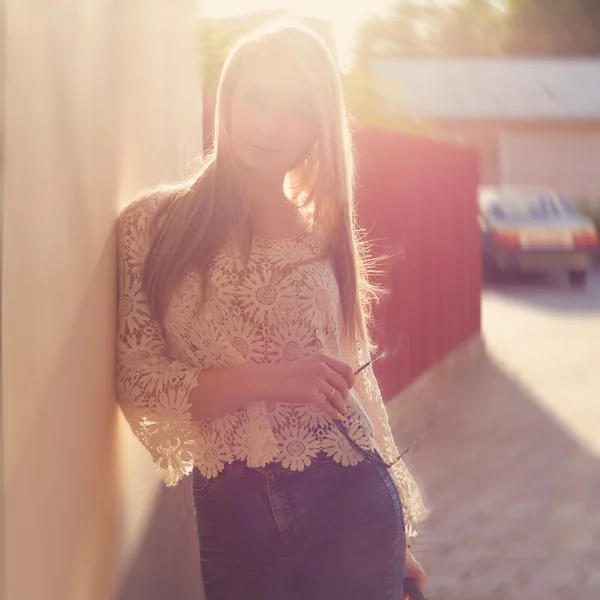 Mooie sexy inschrijving meisje in de buurt van de muur, naast een houten hek bij zonsondergang in de stad, volntse haar — Stockfoto
