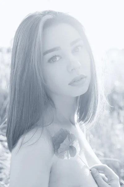 Retrato preto e branco bela menina sexy com lábios gordos com uma flor de papoula na mão com ombros desnudados ao pôr do sol em um campo à luz do sol, sombreando em cores quentes — Fotografia de Stock