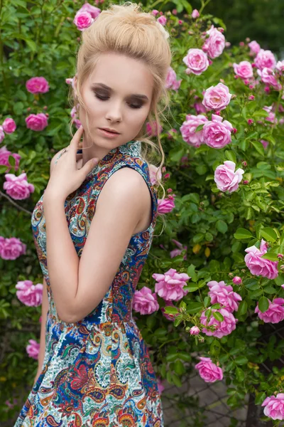 Vackra härliga mjuka sexig tjej nära blommande rosenbuskar i varm sommardag med vackert hår — Stockfoto