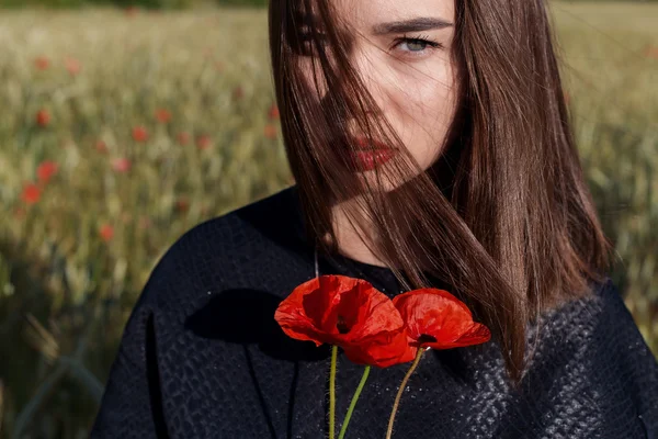 Beautiful sexy cute girl holding poppy flowers in his hands at sunset on a sunny summer day — Stock Photo, Image