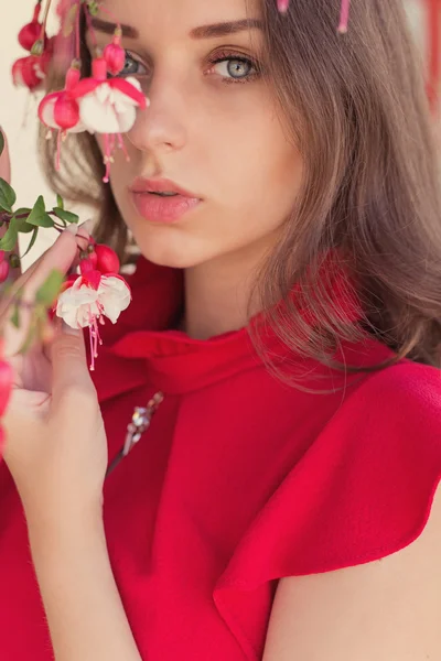 色の近くに立って穏やかな表情で赤いドレスを着た美しいセクシーな女の子 — ストック写真
