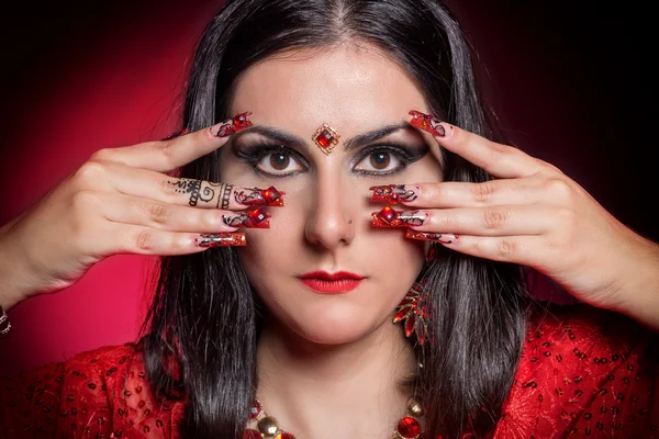 Krásná dívka v obraze indické ženy v červené sárí s krásnou oprava akrylové nehty v orientálním stylu ve studiu — Stock fotografie